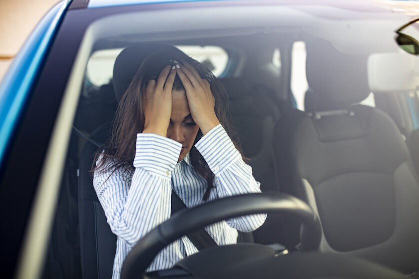 Young woman with hands on eyes sitting depressed in car